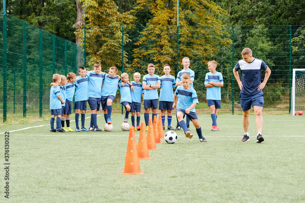 Obraz premium Kids player run and kick soccer balls between soccer chips in soccer training