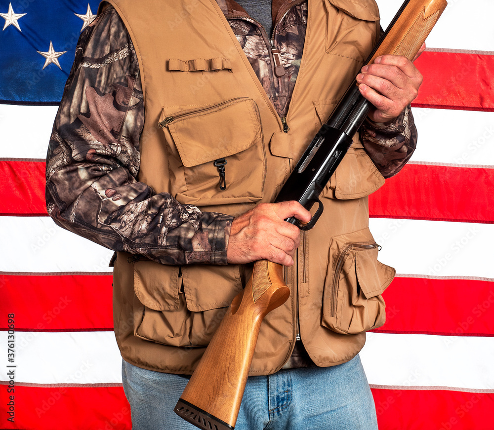 Man holding shotgun while wearing camouflage and hunting vest in front of  American flag, weapon, gun laws, game hunter, sporting rifle, clothes Stock  Photo | Adobe Stock