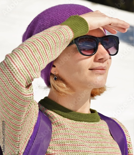 young woman with lilac backpack and hat, in sunglasses outdoors photo