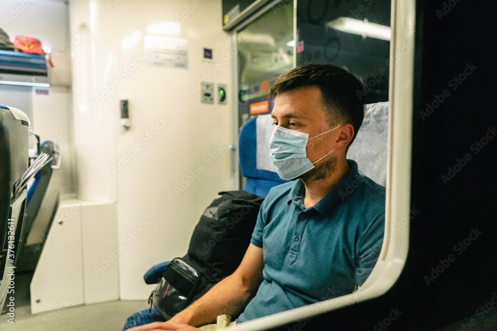 Tired and sad male passenger sits in face shield and looks through the window. View through the window. Topic passenger public transport during coronavirus pandemic. New rules of life covid 19 Tired and sad male passenger sits in face shield and looks through the window. View through the window. Topic passenger public transport during coronavirus pandemic. New rules of life covid 19