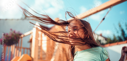 Foto Portrait of a happy little girl sitting on a swing with long hair flying