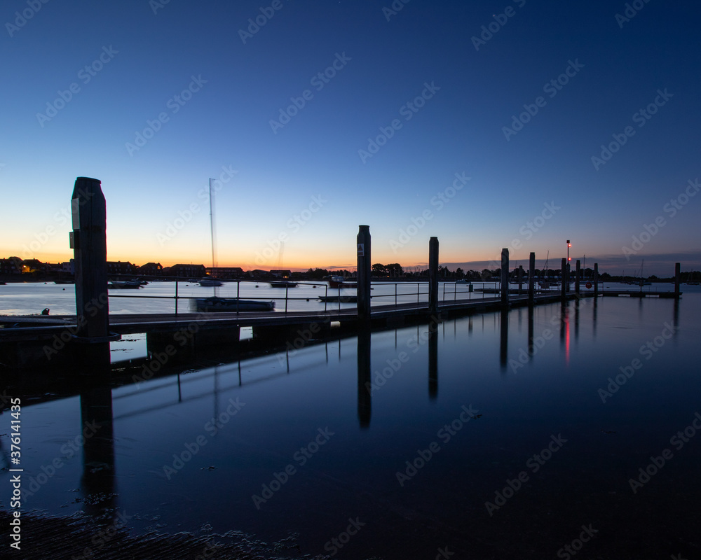 a marina jetty just before dawn with calm waters
