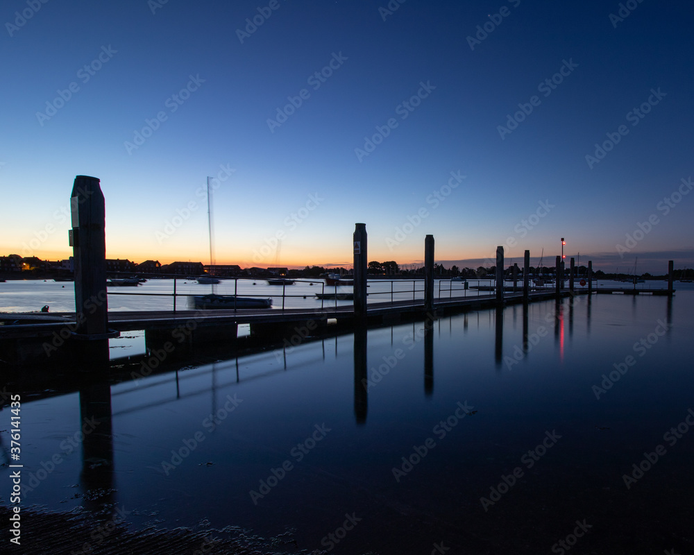 a marina jetty just before dawn with calm waters a marina jetty just before dawn with calm waters