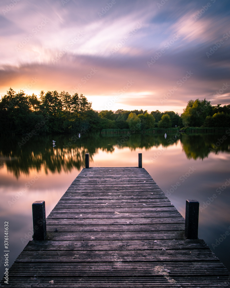 A wooden jetty on a lake at sunset