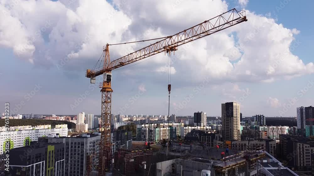 Aerial view of on construction site industrial tower crane. Crane work with the city In the Background. Upward movement with camera tilt revealing construction site from above. Aerial view of on construction site industrial tower crane. Crane work with the city In the Background. Upward movement with camera tilt revealing construction site from above.