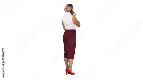 Standing young beautiful woman using a mobile phone making a call on white background.