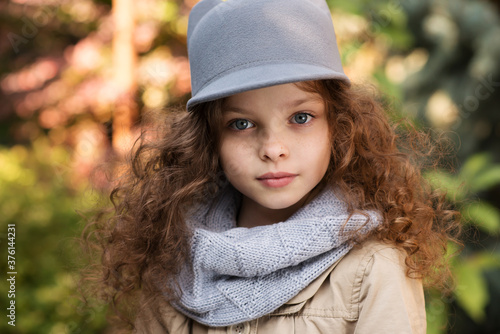 Portrait of little cute smiling girl in funny cat hat with long curly hair.