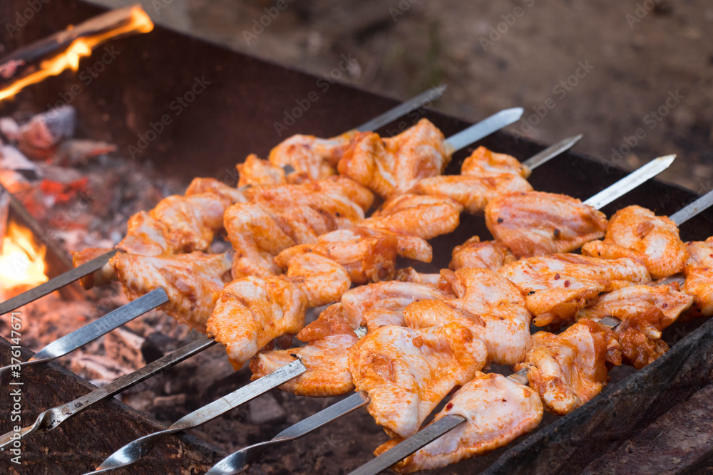Chicken wings kebabs on the barbecue. Cooking delicious juicy chicken wings at outdoors grill