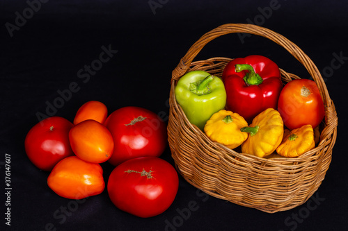 Colorful organic vegetables in wicker basket on black background. Tomato, squash, zucchini, pepper. Autumn harvest. Space for text. photo