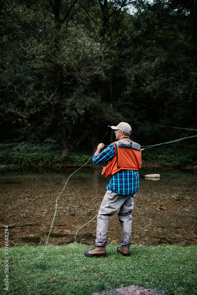 Senior man is fishing alone on fast mountain river. Active people and sport fly fishing concept. Senior man is fishing alone on fast mountain river. Active people and sport fly fishing concept.