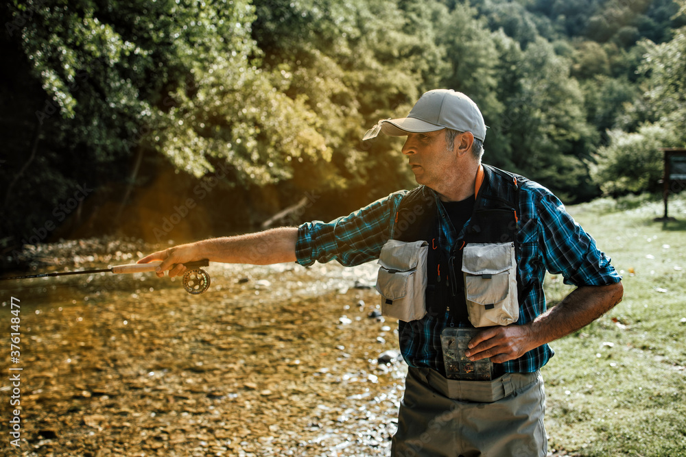 Senior man is fishing alone on fast mountain river. Active people and sport fly fishing concept. Senior man is fishing alone on fast mountain river. Active people and sport fly fishing concept.
