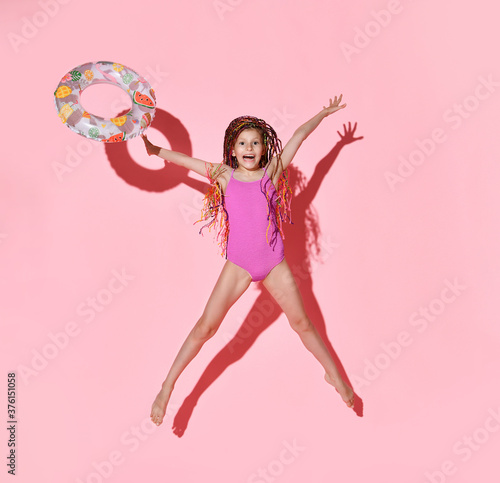 фотографія Happy girl with bright cornrows in one-piece rose swimsuit jumping and screaming