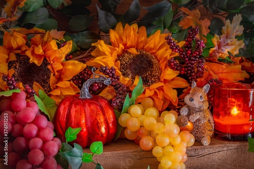 Sunflowers, grapes, and a critter  fill a decorated Thanksgiving mantel.