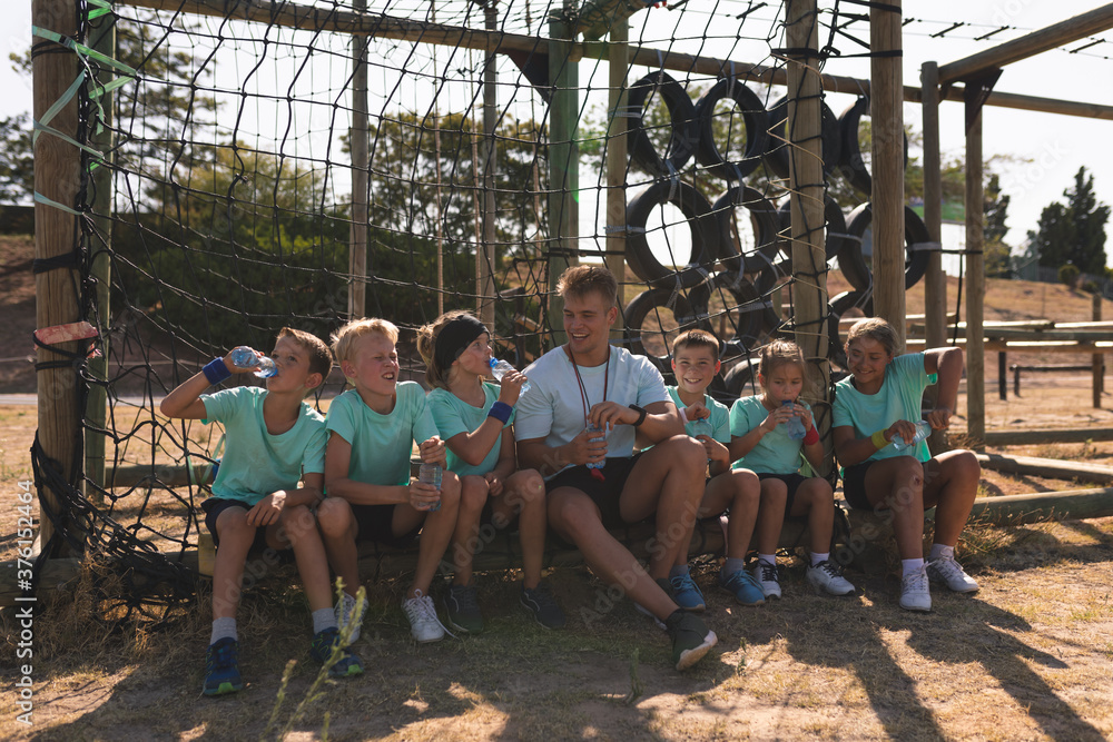 Male fitness coach and kids drinking water at a boot camp Male fitness coach and kids drinking water at a boot camp