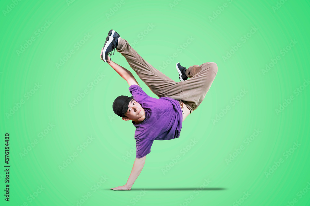 Male dancer showing break dance movement on studio - obrazy, fototapety, plakaty 