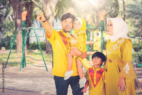 Muslim parents show something to children at park © Creativa Images