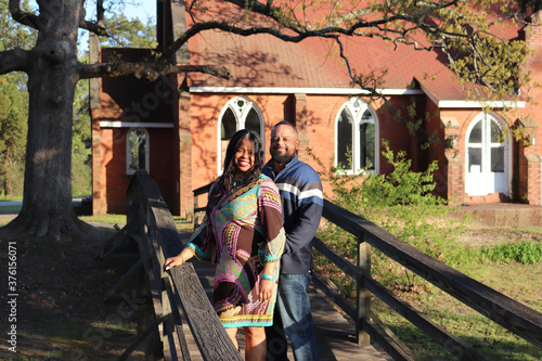 African American couple standing on a bridge by a church on a sunny day © Fillmore