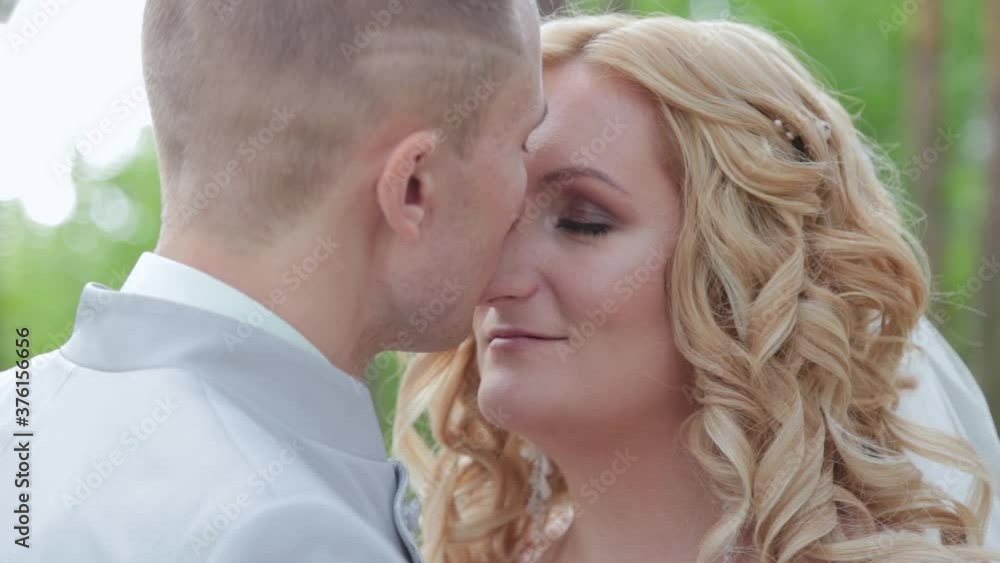 Gorgeous bride and groom hugging and kissing in summer forest.