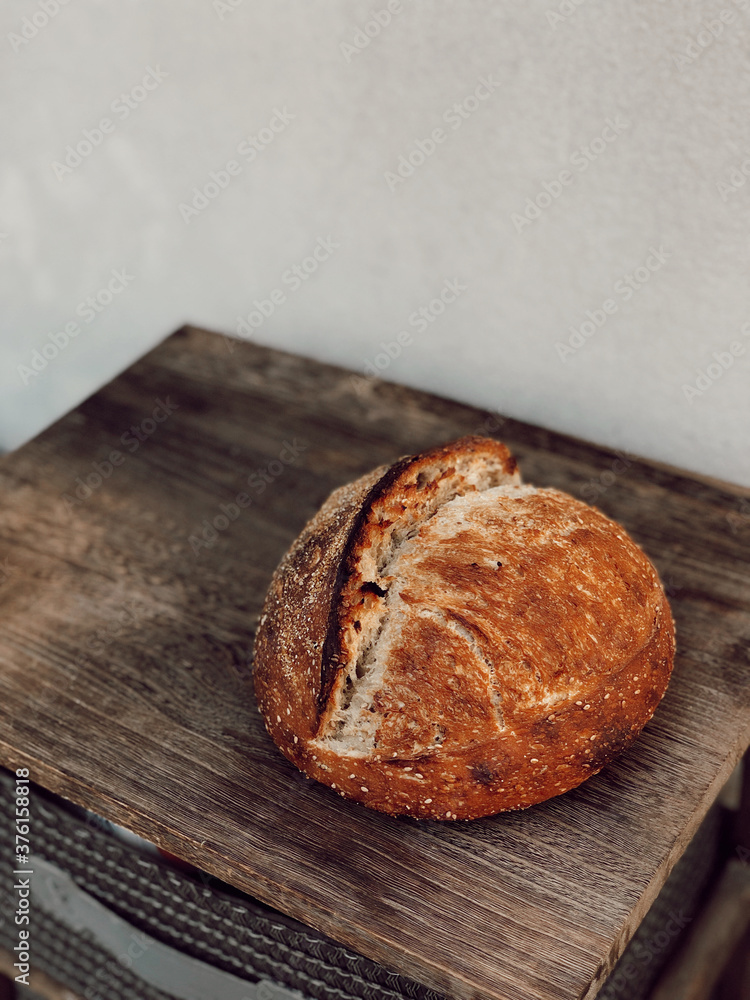 High hydration bread, long and slow cold fermentation, made from wheat flour sourdough just out of the oven on wooden table, banneton and black background