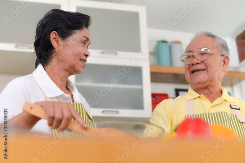 grandfather and  grandmother cooking salad in kitchen room looking tablet.family concept. photo