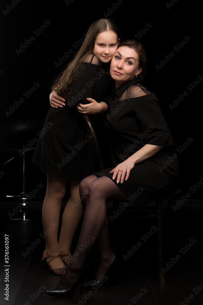 Mom and daughter in the studio on a black background.