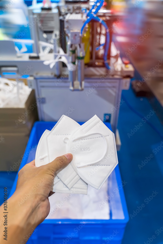hand with mask with automatic machine for the manufacture of medical masks with nanofiber. Coronavirus and Covid-19 Protection hand with mask with automatic machine for the manufacture of medical masks with nanofiber. Coronavirus and Covid-19 Protection