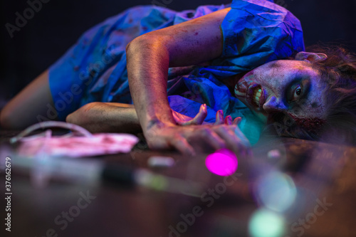 Halloween zombie with coronavirus Woman wearing face mask protective for Covid-19 reaching for the antidote on the floor. Horror infection concept photo