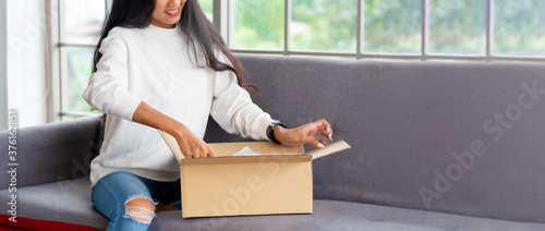 Картината върху платно asian woman satisfied and smile unpack parcel on sofa at home
