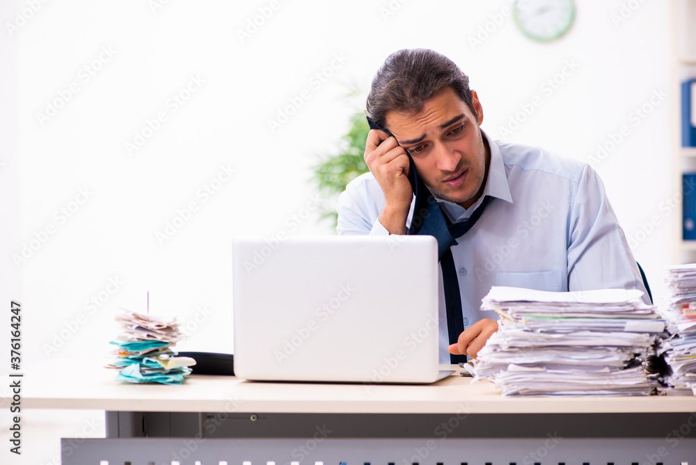 Young male employee unhappy with excessive work Young male employee unhappy with excessive work