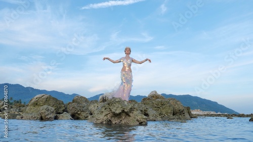 Fairy woman posing at sea rocky shore