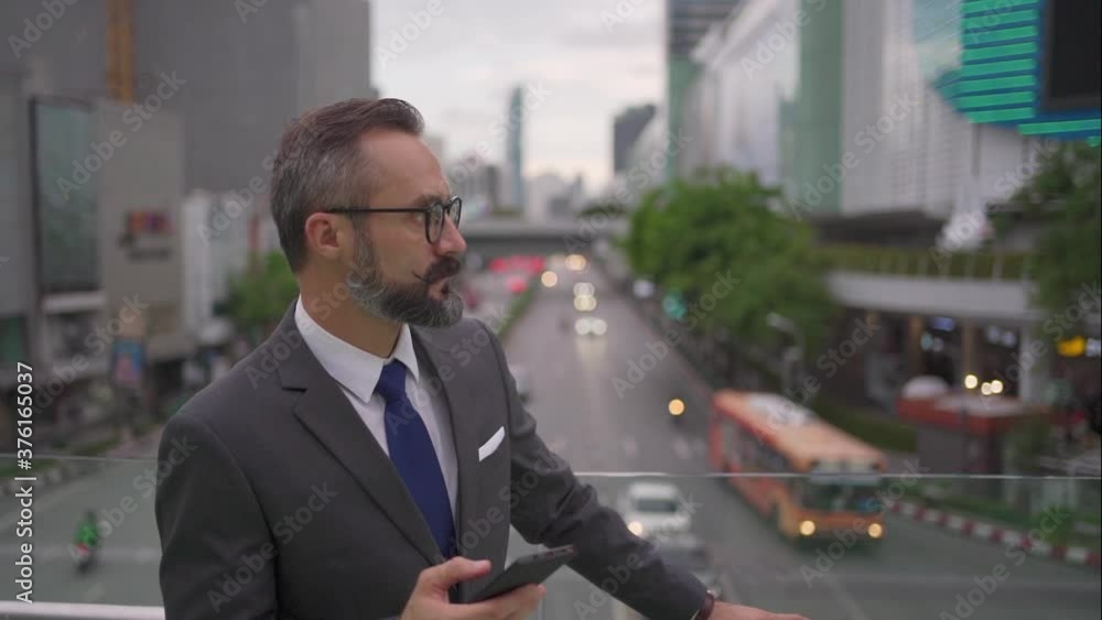 Confidence Caucasian businessman office worker in suit using smartphone with internet and mobile application booking a taxi or texting online message in the city with traffic driving car on the road.