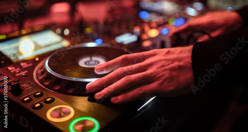 A male DJ is mixing songs on his players on stage as fun, youth, entertainment and stage festivals.