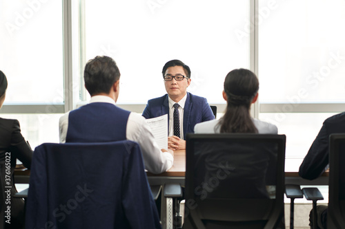young asian business man being interviewed by a group of corporate hr executives