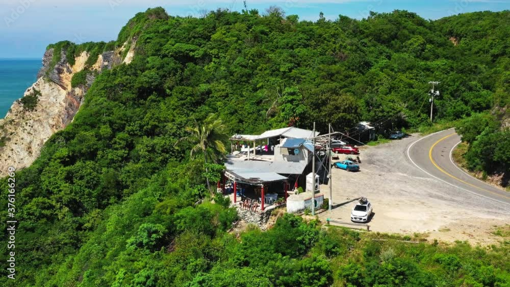 Aerial: ramshackle cafe hut on cliff, overlooking Mexican Pacific Coast