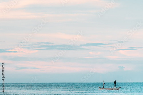Indonesian fishermen fishing at sunset, pink and blue sky over calm ocean photo