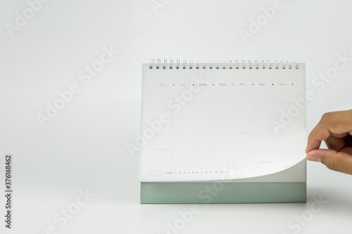Close-up hand is open the blank calendar on a white background with copy space composition.