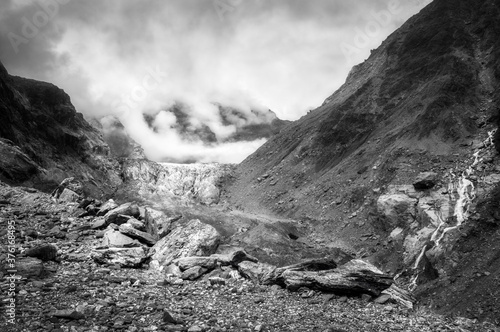 Dramatic view in black and white from Robert's Point Track at Franz Josef Glacier surrounded by mountain peaks covered in clouds in Westland Tai Poutini National Park in New Zealand's Southern Alps.