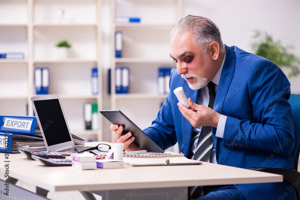 Old face injured employee sitting in the office