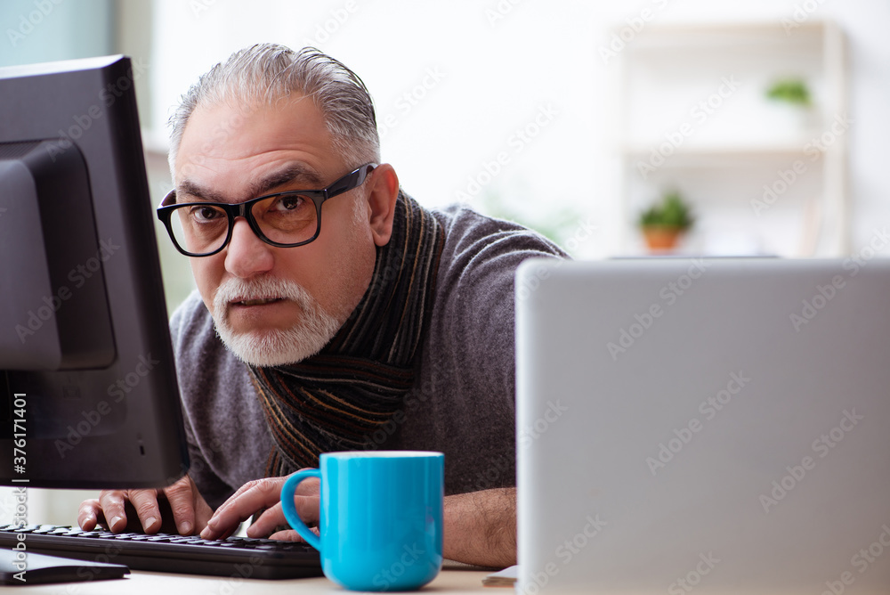 Old male employee working from house during pandemic
