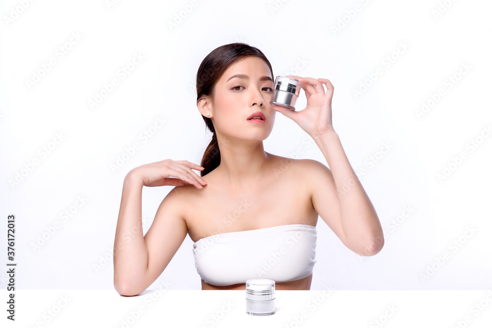 Portrait of beautiful charming young Asian woman posing facial with cosmetic and sitting with white table, beauty of female face with skincare on white background, healthcare and skin care concept. Portrait of beautiful charming young Asian woman posing facial with cosmetic and sitting with white table, beauty of female face with skincare on white background, healthcare and skin care concept.