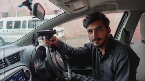 close up of a young man in a car holding a gun