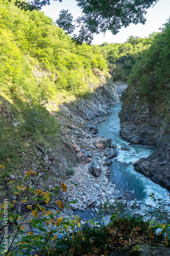 Mountain river canyon in a stone granite gorge with vegetation along the banks on a Sunny summer morning.