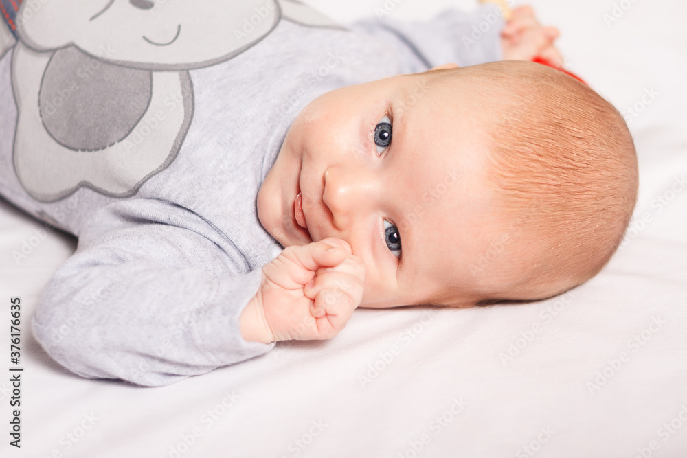 Newborn baby boy smiles lies on white background indoor closeup. Happy, cute and pretty. Home care and cozy. Motherhood Newborn baby boy smiles lies on white background indoor closeup. Happy, cute and pretty. Home care and cozy. Motherhood