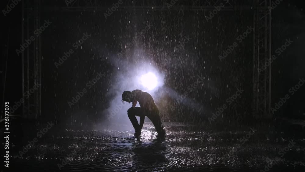 Sensual erotic contemporary dance in the smoke among the raindrops. A young man smoothly moves along the surface of the water, forming many splashes. Contemp choreography. Slow motion. Sensual erotic contemporary dance in the smoke among the raindrops. A young man smoothly moves along the surface of the water, forming many splashes. Contemp choreography. Slow motion.