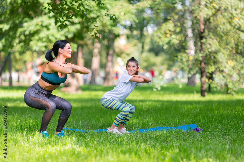 Mom and daughter working out together in the public park