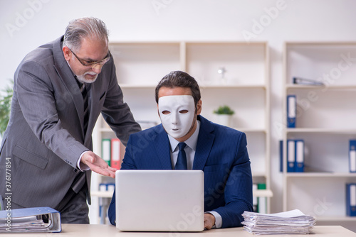 Old boss and young male employee wearing masks