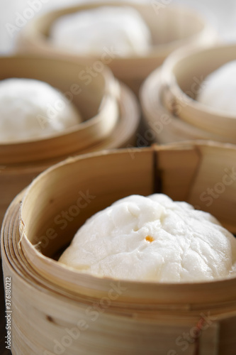 hot red pork filled steamed stuff bun or white bread with point in wooden basket for morning food or breakfast and dim sum snack at restaurant on vertical