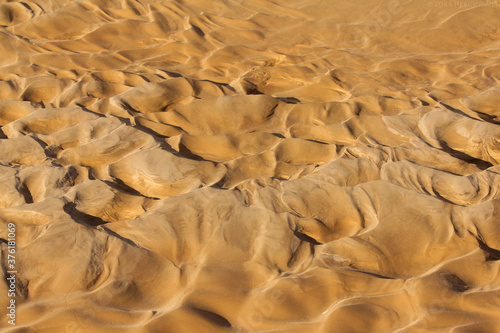 Earth as an element, sand dunes interacting with water at the bottom of the river bed, taken after water drying, brown sand forming hills, abstract landscape 