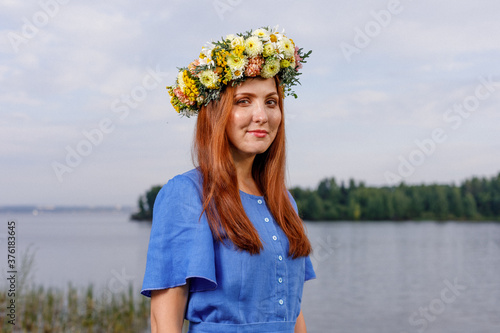 Slavic beauty with a flower wreath on her head in the lap of nature. Ancient pagan origin celebration concept. Summer solstice day. Mid summer. Ancient rituals. photo