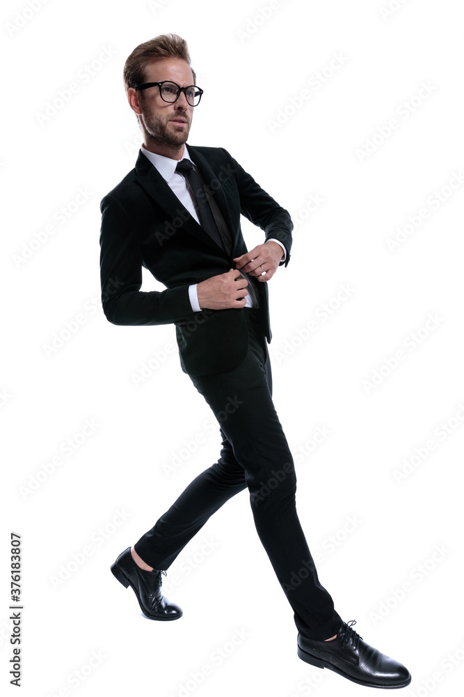 dramatic young man in black suit buttoning jacket dramatic young man in black suit buttoning jacket